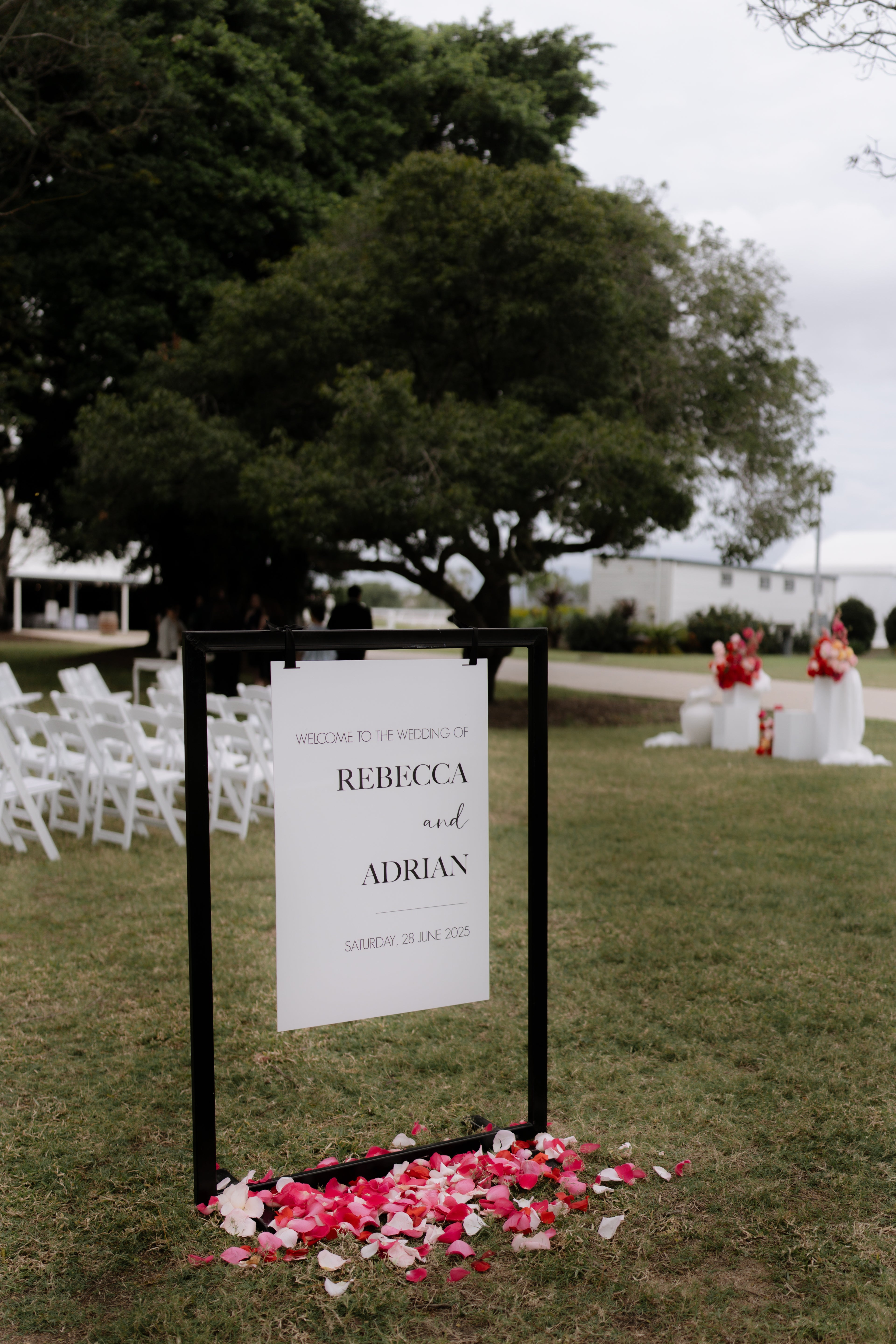 Wedding welcome sign with floral base on grassy area with black metal stand