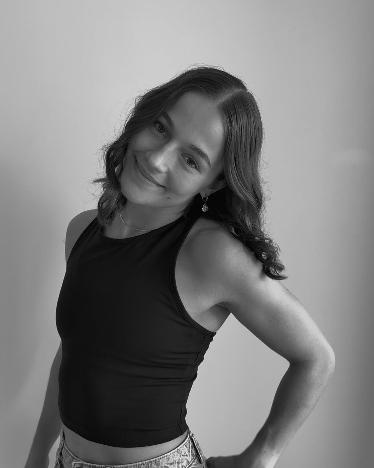 Black and white photo of a person wearing a black tank top and jeans.